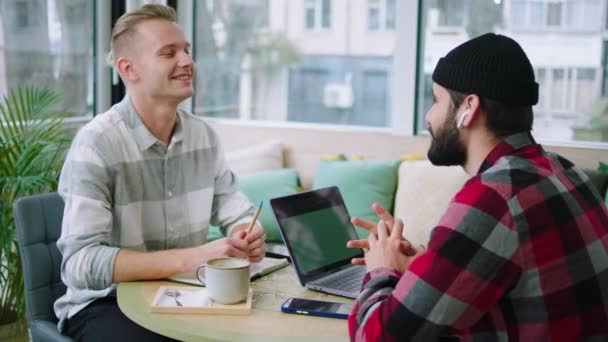 Voor de camera charismatisch goed uitziende jonge jongens te bespreken in de coffeeshop ze studeren samen op dezelfde universiteit — Stockvideo