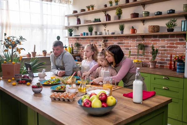 På den moderna rustika köksön ger den karismatiske pappan tillsammans med sina döttrar som förbereder frukosten lite färsk apelsinjuice till sin dotter — Stockfoto