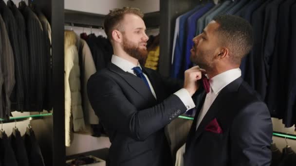 Handsome consultant man in the luxury suit shop helping the client to wear the bow to over the suit client are very charismatic Afro American businessman concept of hand craft design couture and — Vídeo de Stock