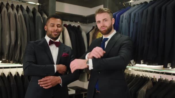 In the suit shop two handsome men multiracial in the suit posing and crossing hands in front of the camera — Vídeo de Stock