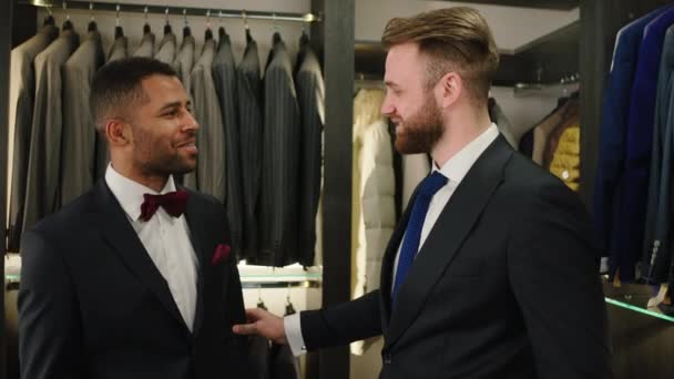 Hombre afroamericano guapo tener una conversación con el consultor de ventas en la tienda de trajes de lujo — Vídeos de Stock