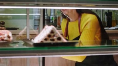 Kameranın önünde, kafeteryada çalışan koruyucu maskeli bir satıcıyı koronavirüs salgınında yakalar ve vitrine taze çöl koyar.