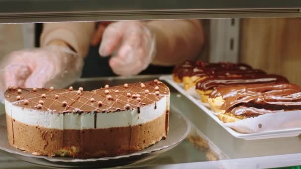 In the bakery cafe closeup to the camera capturing video of a salesman arrange carefully chocolate cake from the showcase fridge. . Shot on ARRI Alexa Mini. — Stock Video