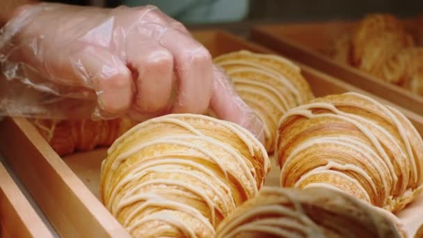 Details closeup in the bakery shop salesman take some fresh croissants from the showcase fridge. . Shot on ARRI Alexa Mini. — Vídeo de stock