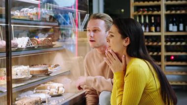 Pastanede, karizmatik ve güzel bir kadınla partneri birlikte vitrin dolabındaki lezzetli tatlıya bakıyorlardı. 4k