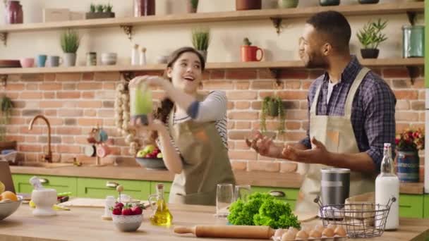 In the morning young couple multiracial preparing the breakfast together at the kitchen island they shake the smoothie then add in the glasses get ready to drink — Stockvideo