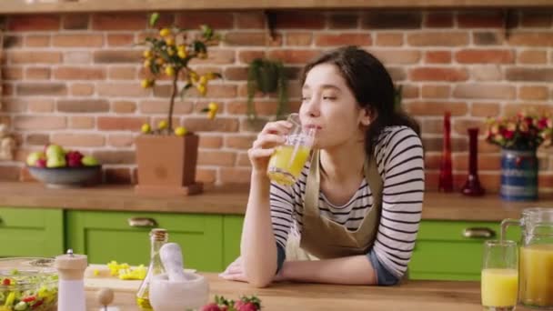 Very enthusiastic lady at her kitchen island enjoy the morning while she is alone she take some fresh juice and drink in front of the camera — Stock video