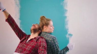 Kameraya yakın karizmatik çift büyük bir gülümseme ile duvarlar için yeni yenileme yaparken onları yeni bir renge boyamaya birlikte dans etmeye ve duvar fırçalarını ellerinde tutmaya başlarlar.