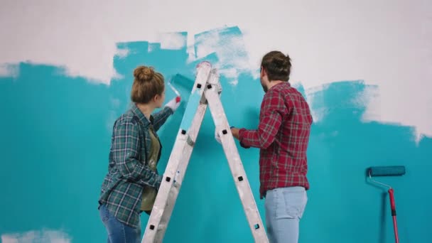 Przed kamerą skoncentrowała się para pracująca w domu malując ściany w niebieskim kolorze i dając pięć za dobry zespół, który stoi na wadze. — Wideo stockowe