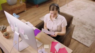 Genç üniversite öğretmeni online dersleri için hazırlan. Oturma odasındaki ödevine bakarken gülümsüyor. ARRI Alexa Mini 'de çekilen