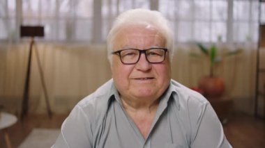 Kameranın önünde resim çeken yakışıklı bir adam dik dik bakıyor ve evde biraz gülümsüyor. 4k