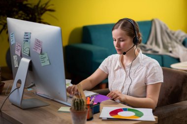 Beautiful young woman professional call centre agent have call conference on the computer at home she wear wireless headset.