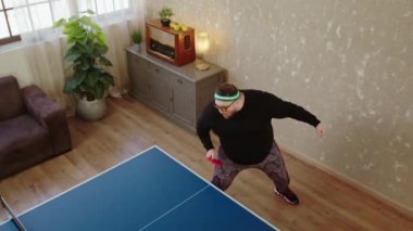 Heyecanlı ve çok mutlu şişman bir adam masa tenisi ya da masa tenisinde oynuyor. Yeni raketiyle topu yakalayıp vuruyor.