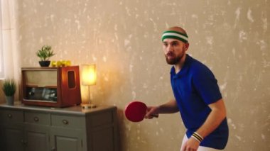 Spor anlayışı ve sağlıklı yaşam tarzı. Pinpon oynayan genç adam çok heyecanlı. Bütün topları kırmızı raketle yakalıyor. 4k