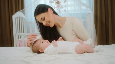 Annesinin kucağındaki tatlı bir kızın kamera önünde portresi bebek emzirme ve çocukluk kamera konseptine bakıyor. Portre