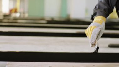 Kamera detaylarına yakından bakınca inşaat alanında koruyucu eldivenleri ve ekipmanları olan bir inşaat işçisi tarafından yapılan bazı yapı malzemelerini dikkatlice boyuyor. ARRI Alexa Mini 'de çekilen.