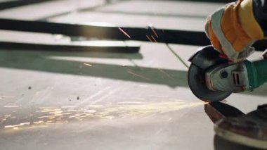 İnşaat alanında çalışan inşaat işçisinin önünde metal kesmek ve koruyucu ekipman ve kask takmak için disk kaynak makinesini kullanıyor. ARRI Alexa Mini 'de çekilen.