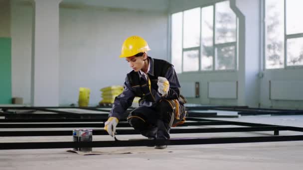 工事現場で小さなブラシで建築材料を塗装安全ヘルメットや機器を持つ集中建設労働者の女性 — ストック動画