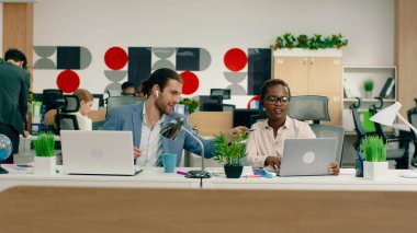 Beyaz, yakışıklı bir adam ve muhteşem siyah bir kadın çalışma masalarında iş hakkında konuşuyorlar.