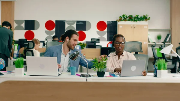 白いハンサムな男と豪華な黒人女性は 彼らの仕事について議論大規模なオフィスで彼らの仕事机にあります — ストック写真