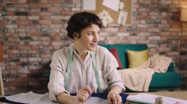 Gülümseyen genç bayan moda tasarımcısı bazı ölçüler alıyor ve terzideki yeni koleksiyon için güzel bir bluz dikmek üzere kumaşları hazırlıyor. 4k