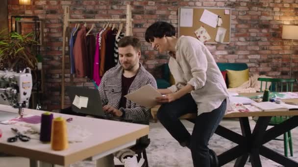 在一个看起来像办公室的设计师办公室里 一个男人和一个女人在笔记本电脑上工作 在他们讨论事情的时候笑着说 气氛很冷 — 图库视频影像