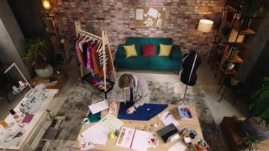 İyi görünümlü tasarımcı çizimlerine bakıyor, müzik dinliyor ve dans ediyor. Yeni koleksiyonu için stüdyoda çalışıyor.