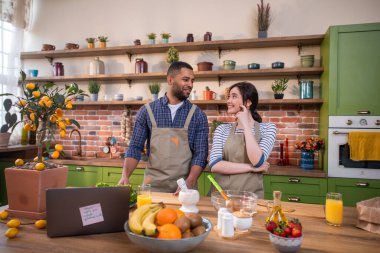Birlikte yemek pişirmek için harika bir zaman. Bir lokanta. Mutfak adasındaki tarifleri okumak için laptopa bakıyorlar..