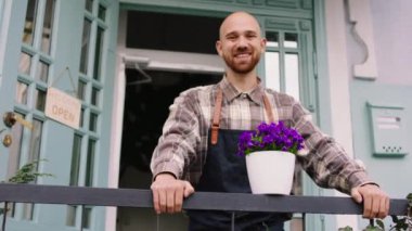 Dükkânın sahibi dükkânın önünde kameranın önünde poz verirken büyük bir gülümseme sergiliyor. 4k