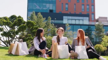 Güzel bir alışveriş yaptıktan sonra arka planda şehrin orta yerinde modern bina mimarisini tartışan bir grup ofis çalışanı. 4k