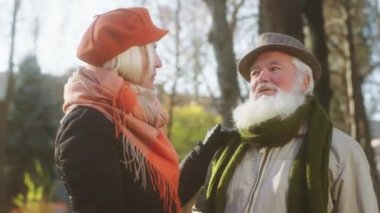 Mükemmel görünümlü yaşlı çift, çok romantik. Soğuk bir sonbahar gününde parkta gezinti yapıyorlar. Birbirlerine sarılıp tartışıyorlar. 4k