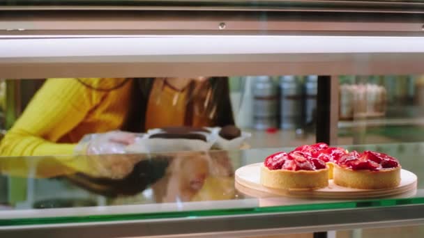 Στο Αρτοποιείο Πωλήτρια Προσθέτει Μερικές Φρέσκες Ερήμους Στο Ψυγείο Βιτρίνα — Αρχείο Βίντεο