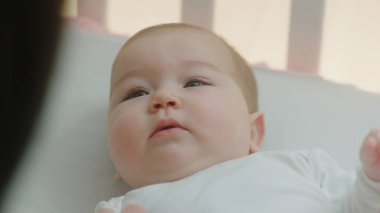 Kameranın önünde karizmatik genç anne bebeğiyle bir sabah rutini yaşar bebeğinin bacaklarını dikkatlice öper. Ayrıntı