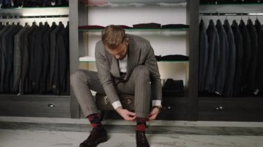 Lüks takım elbise mağazasının yakışıklı müşterisi. Bir çift ayakkabı al ve gitmeye hazır ol. ARRI Alexa Mini 'de çekilen