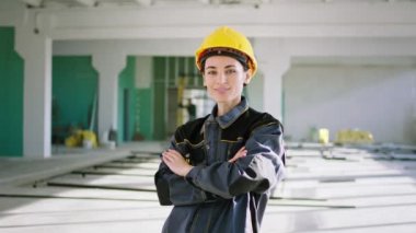 İnşaat alanındaki kameraya yakın çekim yapan genç bayan mühendis kameranın önünde gülümsüyor ve güvenlik ekipmanlarıyla el ele tutuşuyor. ARRI Alexa Mini 'de çekilen.