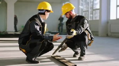 Karizmatik kadın mimar ve inşaat alanında çalışan erkek inşaat işçisi iş için bazı ağır inşaat malzemelerini analiz ediyorlar. 4k