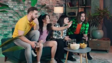 Karizmatik ve iyi görünümlü çok ırklı arkadaşlar oturma odasında bir spor maçı izleyip skoru analiz ediyorlar ve birlikte vakit geçiriyorlar. 4k