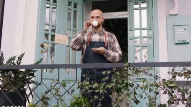 Attractive owner of the floral shop taking his coffee while have a break time outside of the shop concept of small business entrepreneur and florist. Shot on ARRI Alexa Mini