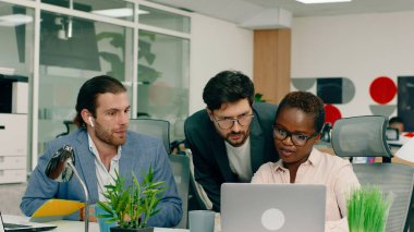 Çok büyük bir ofiste, mavi takım elbiseli çok çekici bir adam gülüyor ve yakışıklı Afrikalı iş arkadaşı arasında konuşuyor..