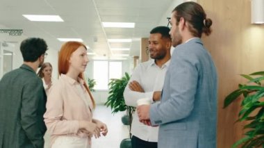 İki yakışıklı iş adamı ve güzel bir kızıl kadın ofis koridorunun ortasında dikilip sohbet ediyorlar.