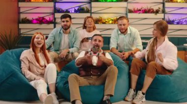 Six people are cheering for each other and celebrating each other s victories as they win in playing video games. Arri Alexa Mini.