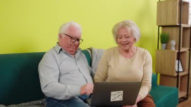 Yakışıklı yaşlı çift laptoptan biriyle görüntülü bir konuşma yapıyor. Heyecanlı bir şekilde gülümsüyor ve zevkle tartışıyorlar. 4k
