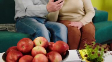 Oturma odasında yaşlı ve çekici bir çift akıllı telefondan görüntülü bir konuşma yapıyor heyecanlı bir şekilde konuşuyorlar ve el ele verip anın tadını çıkarıyorlar..