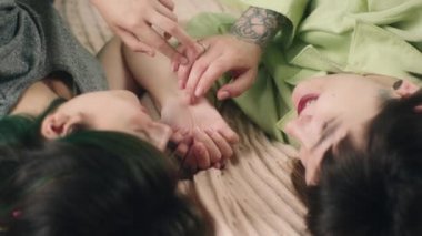Very attractive two young ladies best friends laying down on the bed discussing with each other touching slowly hands concept of LGBT a freedom equality friendship. 4k