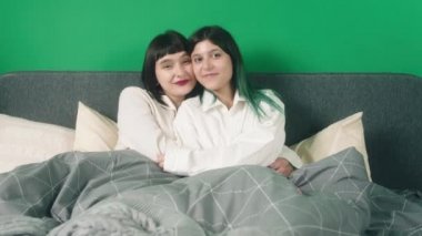 Kameranın önünde iki güzel kadın birbirine sarılıyor ve kameraya bakıp gülümsüyor. 4k