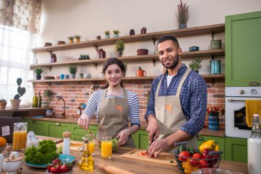 Modern ve büyük mutfak mutlu ve hevesli çift erkek ve güzel beyaz kadın birlikte yemek pişiriyorlar..