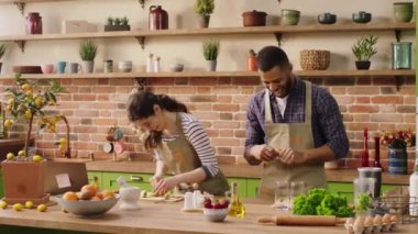Large modern kitchen island excited with a large smile couple multiracial cut some fresh fruits to prepare the healthy breakfast together they discussing and feeling happy. 4k