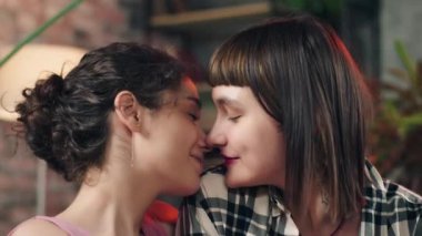 Gülümseyen iki tatlı bayan LGBT lezbiyen çift birbirlerine yakın durup kamera önünde romantik vakit geçiriyorlar.