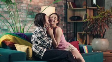 Good looking lesbian couple at home in living room spending romantic time hugging each other and hugging hands concept of LGBT equality freedom