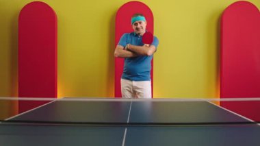 Yaşlı adam masa tenisine başlamadan önce kameranın önünde poz verirken çok çekici gülümsüyor ve elinde kırmızı raket tutuyordu. ARRI Alexa Mini 'de çekilen